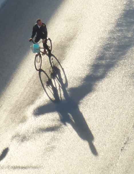 An overhead view of a bicyclist with a blue bag in his basket